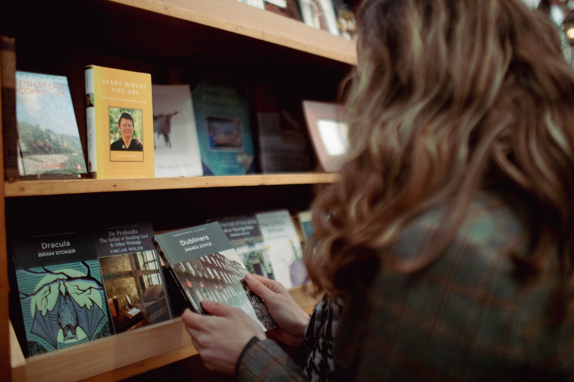 A girl with red, long wavy hair looking at a book in Stokes Bookstore.