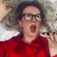 A woman in bright red shirt is shouting into a phone she is holding