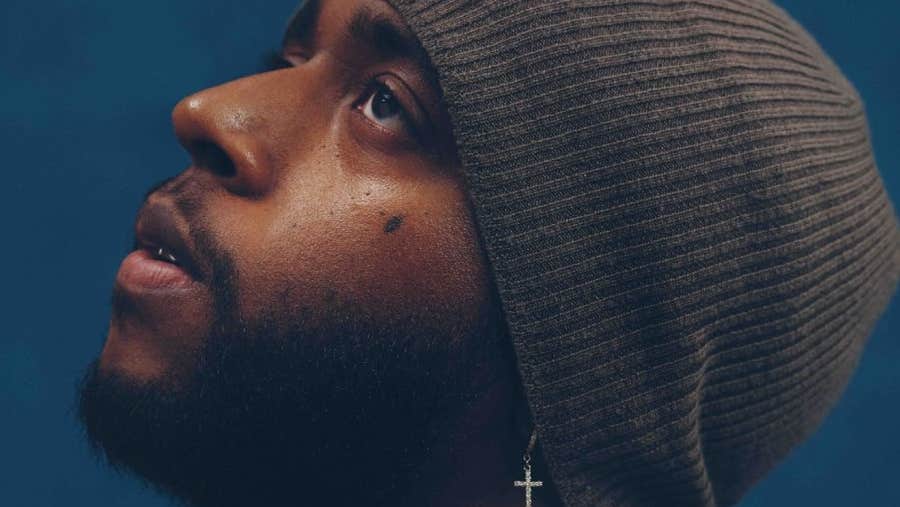 A side profile of man wearing a wooly hat, looking slightly upwards.