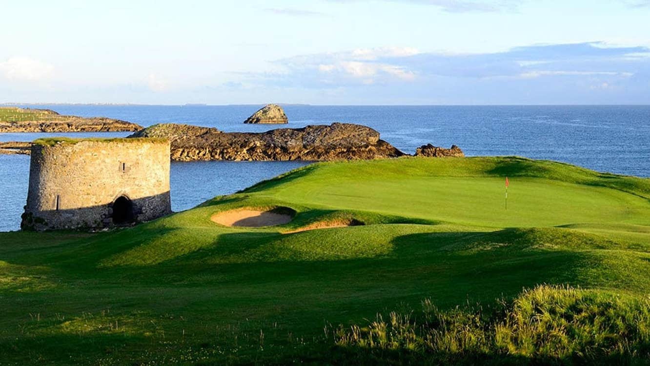 A golf course near the sea with a round tower