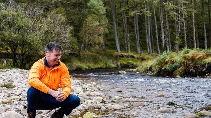 A man crouching beside a stream in the Wild Nephin National Park in Mayo. 