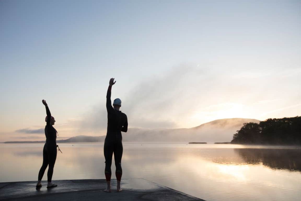 Two swimmers stretching at sunrise in County Clare