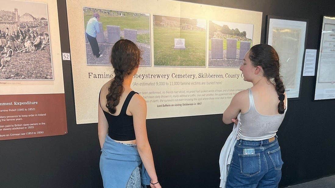 Two people reading information off a storyboard set on a black wall