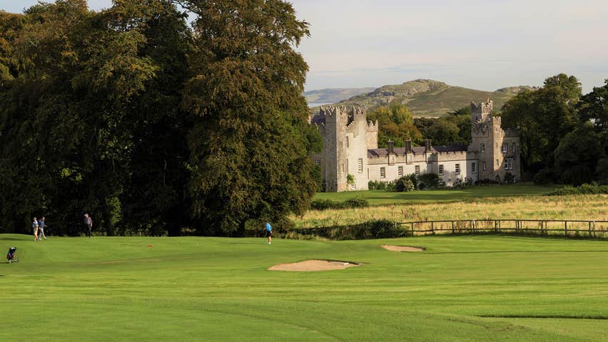 Golfers on a golf course with a castle the background