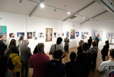 Person giving a talk to a group of people standing in an exhibition room