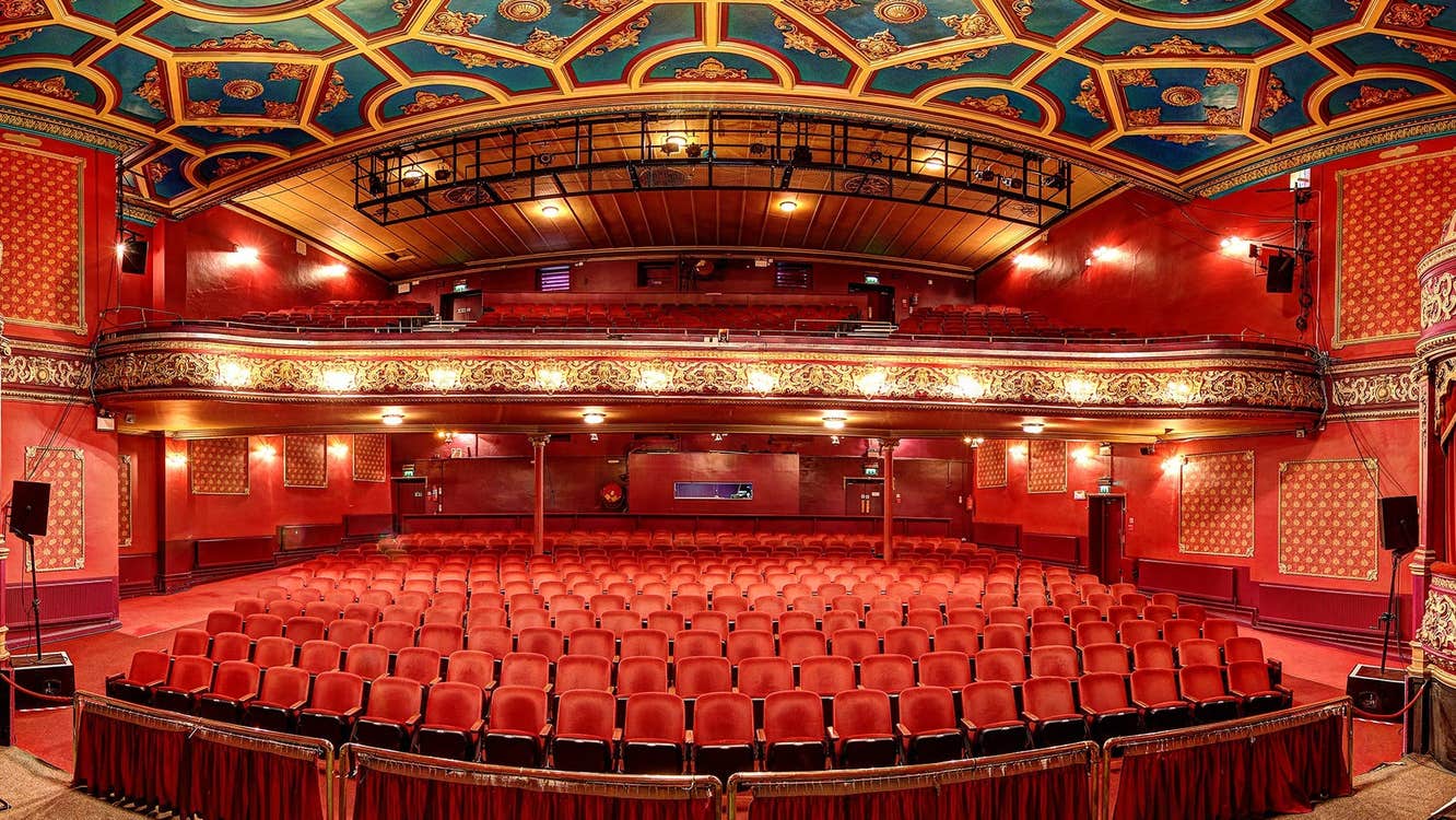 Empty auditorium with rows of red seats and a blue and gold ceiling