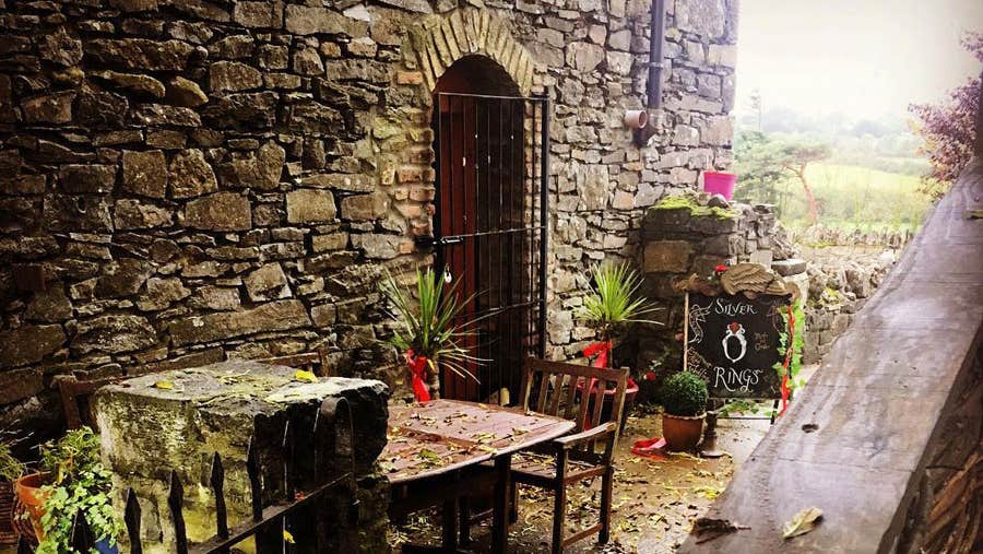 Old stone building and courtyard with a table and colourful plants in Rathcormac Craft Village in Branley's Yard
