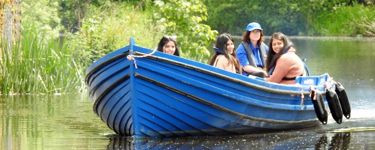 Three girls on a blue boat on the river with the Skipper steering