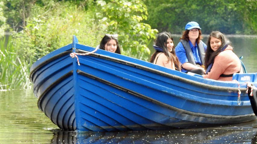 Three girls on a blue boat on the river with the Skipper steering