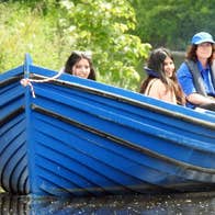 Three girls on a blue boat on the river with the Skipper steering