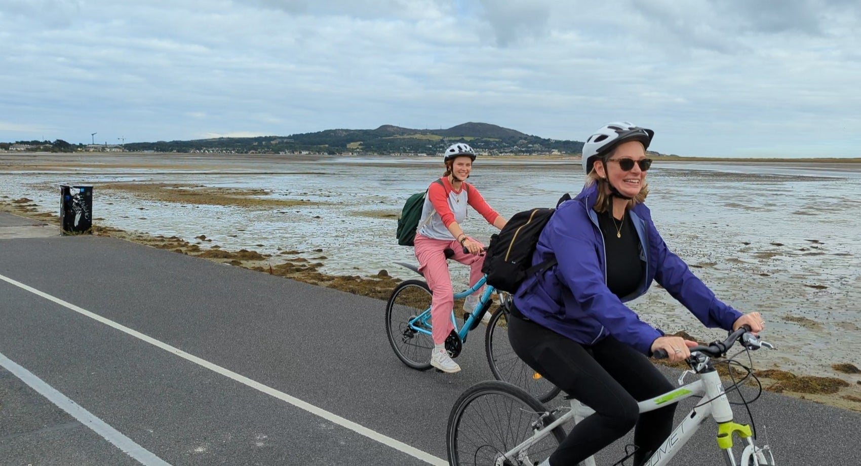 Two ladies on hybrid bikes cycling along the coast