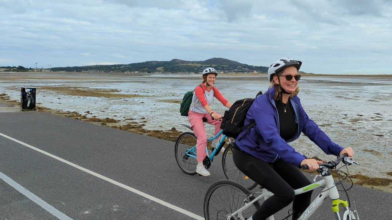 Two ladies on hybrid bikes cycling along the coast