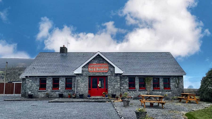 Stone faced house with parking area.