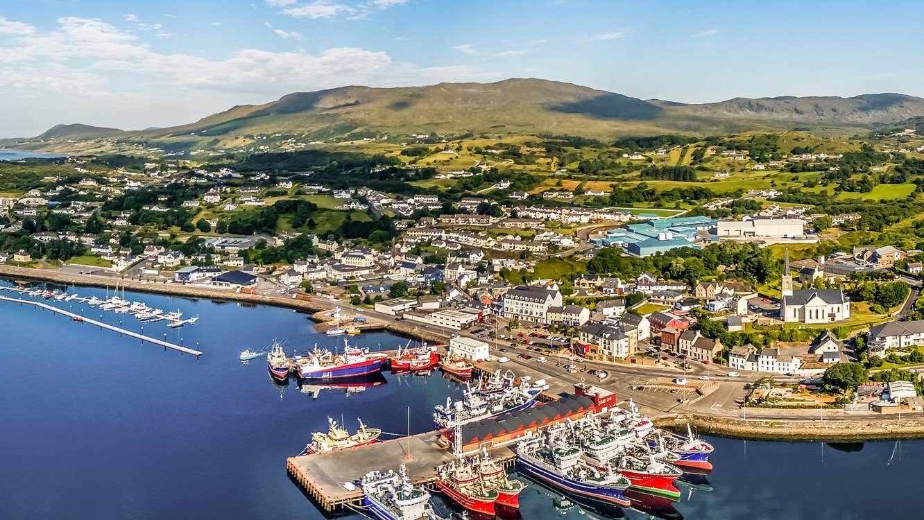 Red and blue and white boats moored at a harbour with image taken from the sky