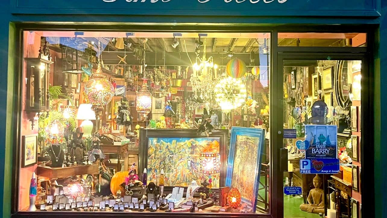 Blue shop front with a wooden door and window surround displaying jewellery and art