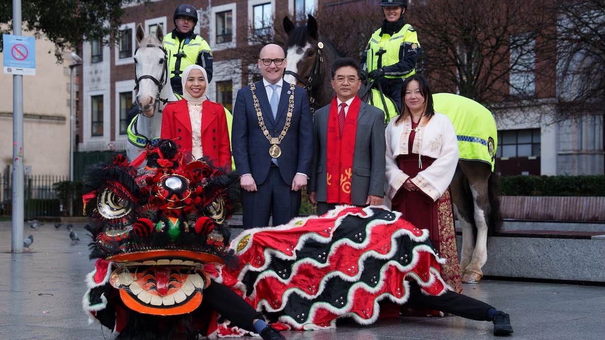A group of smiling people including 2 on horses and a dragon