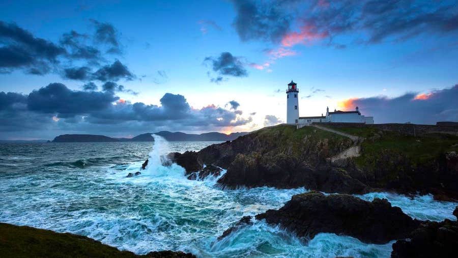 Fanad Lighthouse at sunset with foaming sea in foreground