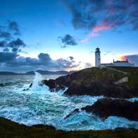 Fanad Lighthouse at sunset with foaming sea in foreground