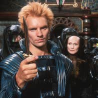 A man with a knife is standing in front of a group of people. They are wearing futuristic clothes.