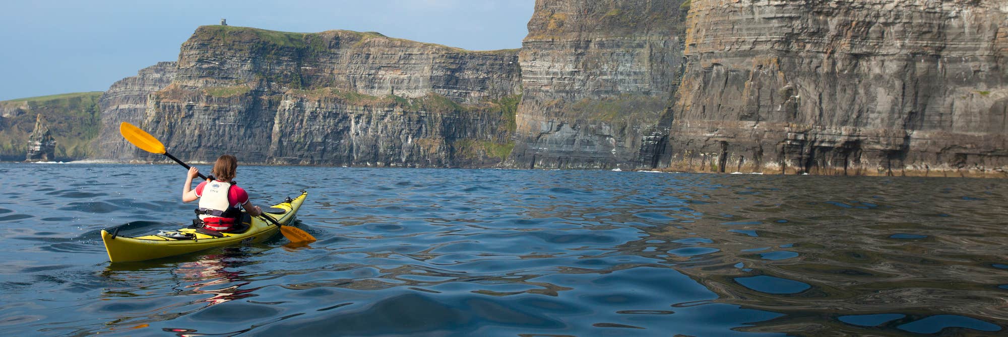 A person kayaking by the Cliffs of Moher in County Clare