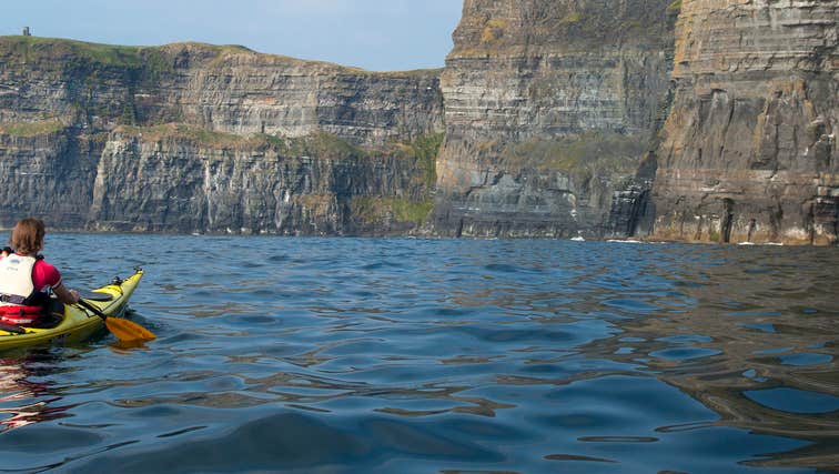 A person kayaking by the Cliffs of Moher in County Clare