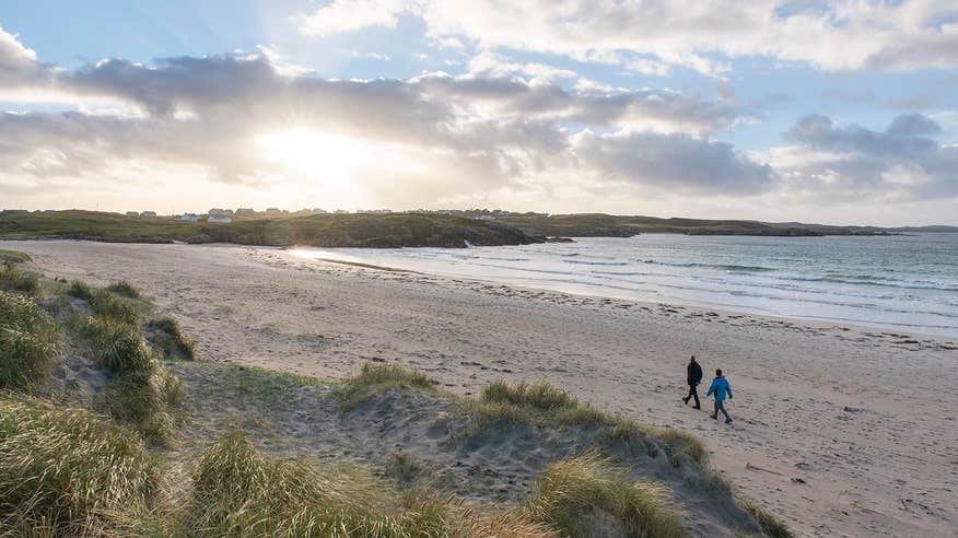 Two people walking down the empty Carrickfinn Beach, Gweedore, Donegal