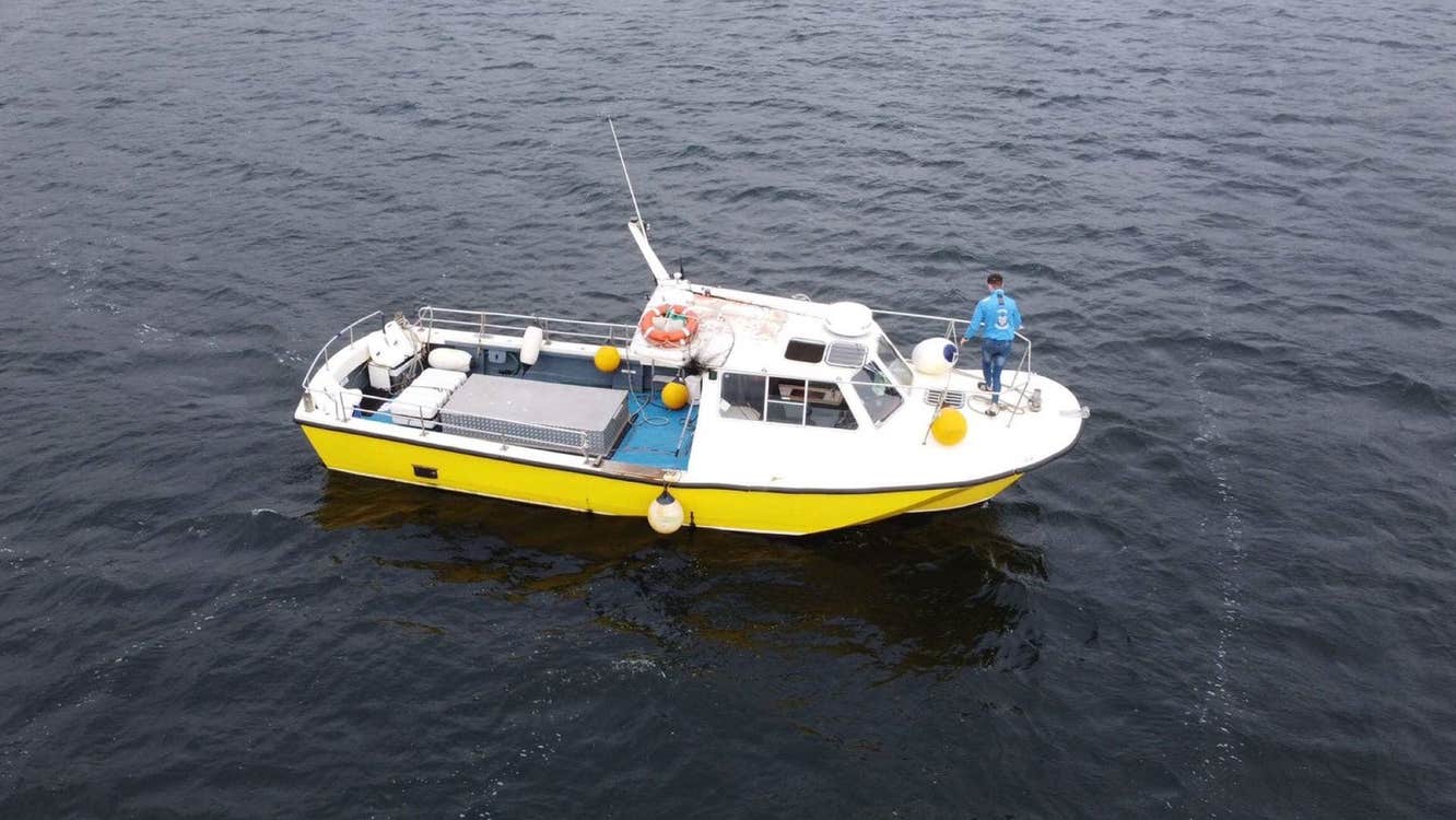 Aerial view of a small white and yellow boat anchored at sea