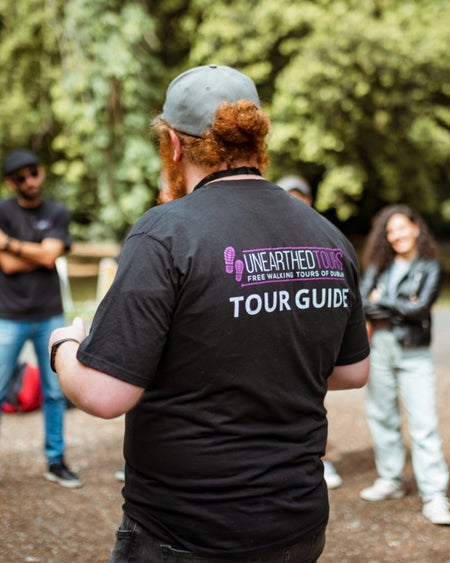 A guide wearing branded clothing of a tour company while giving a tour