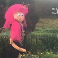 Scarecrow at Skerries Mills - a tall figure with bright pink long hair and large face outside in a garden