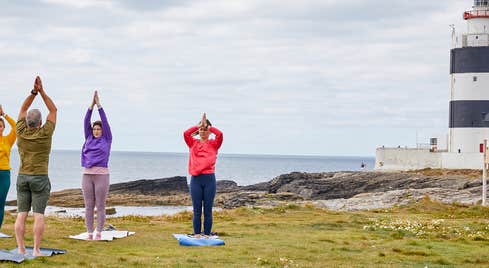 People doing yoga in front of Hook Head Lighthouse.