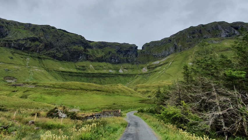 A small country road leading towards a ridge of mountains