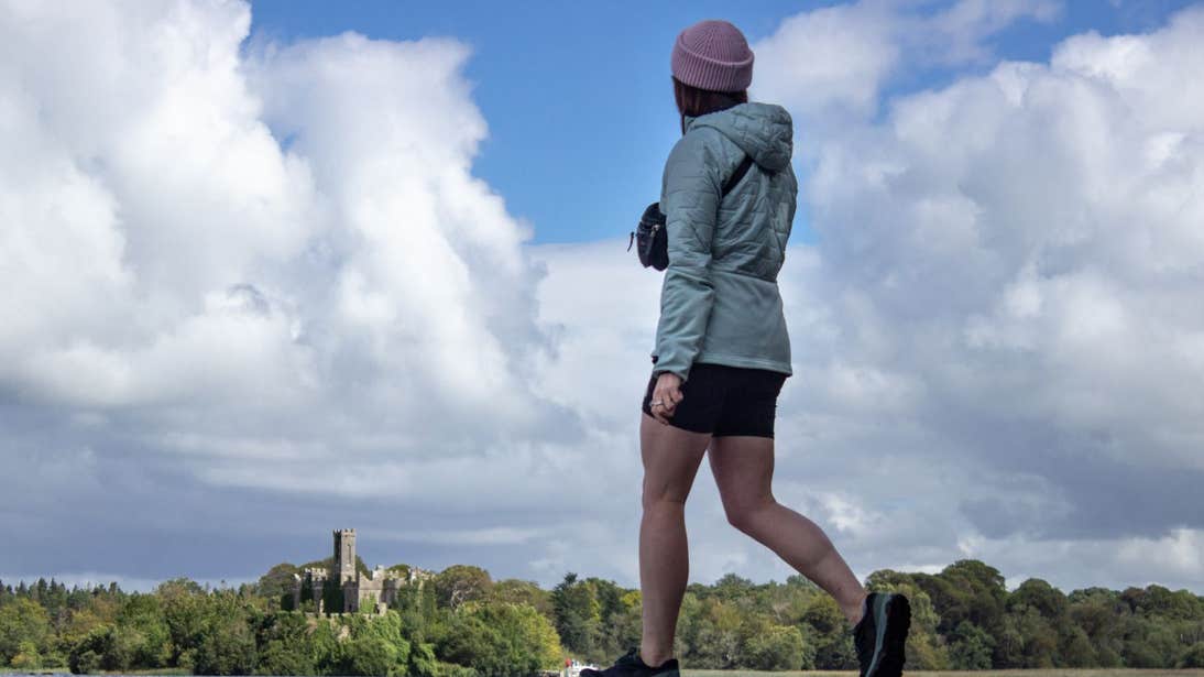 A girl walking with a view of a castle in the background at Lough Key, Roscommon