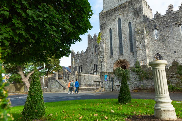 Three people walking the grounds of St Mary's Cathedral in Limerick.