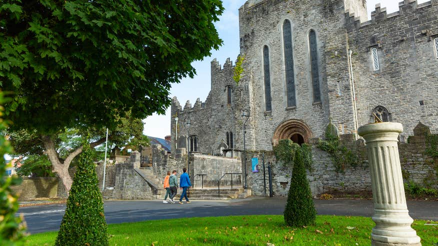 Three people walking the grounds of St Mary's Cathedral in Limerick.