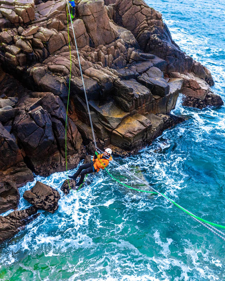 A man Tyrolean Traversing on Cruit Island in County Donegal