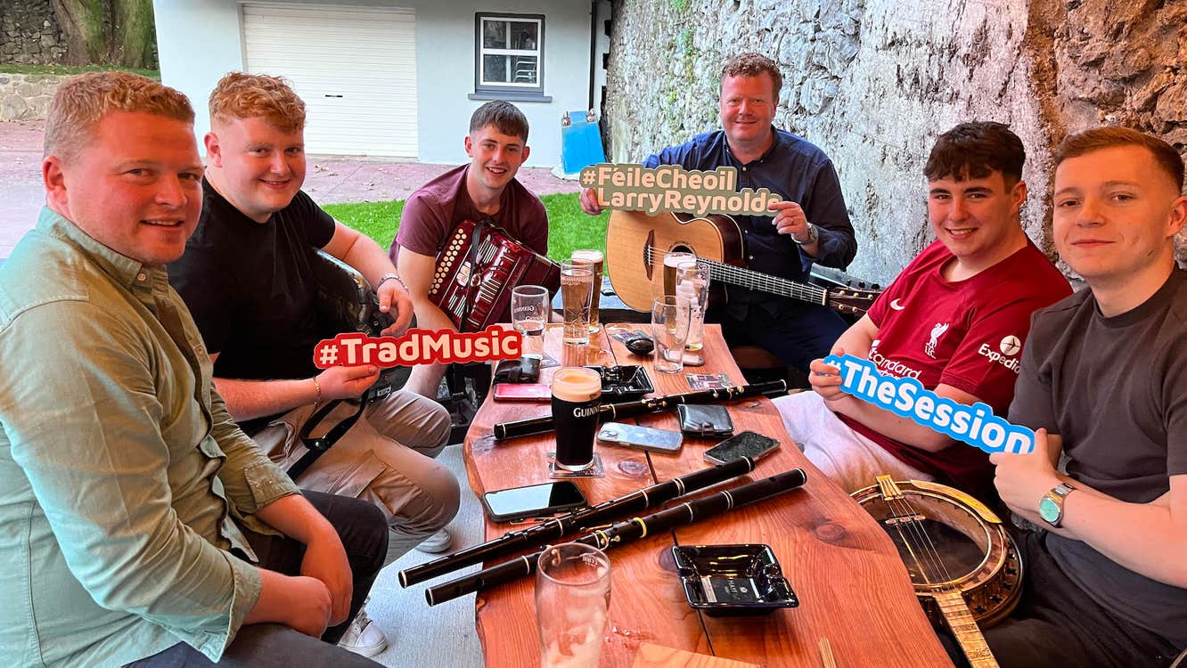 Live Music Session with top musicians in Beer Garden, 6 seated around a table outdoors with musical instruments