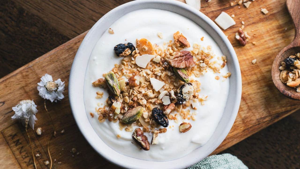 A bowl of creamy yoghurt topped with crunchy granola and dried fruits