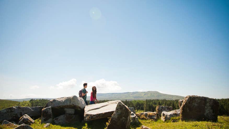 Two people walking by rocks and stone structures in Cavan Burren Park