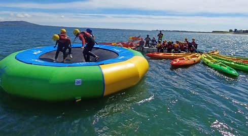 People on an inflatable water platform with kayaks behind it at Carlingford Adventure Centre