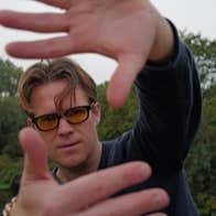 View of man with his hands held up at arms length framing his face.