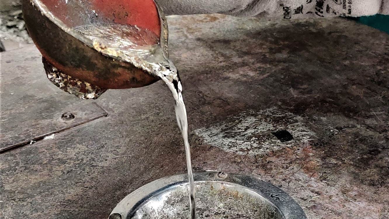 Copper pot pouring melted silver into a silver pot