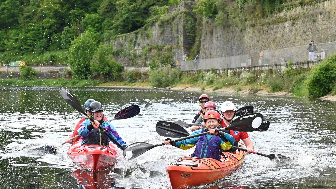 A group of people on the River Nore beneath Kilkenny Castle in double kayaks