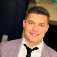 A smiling man in grey jacket and loose black tie