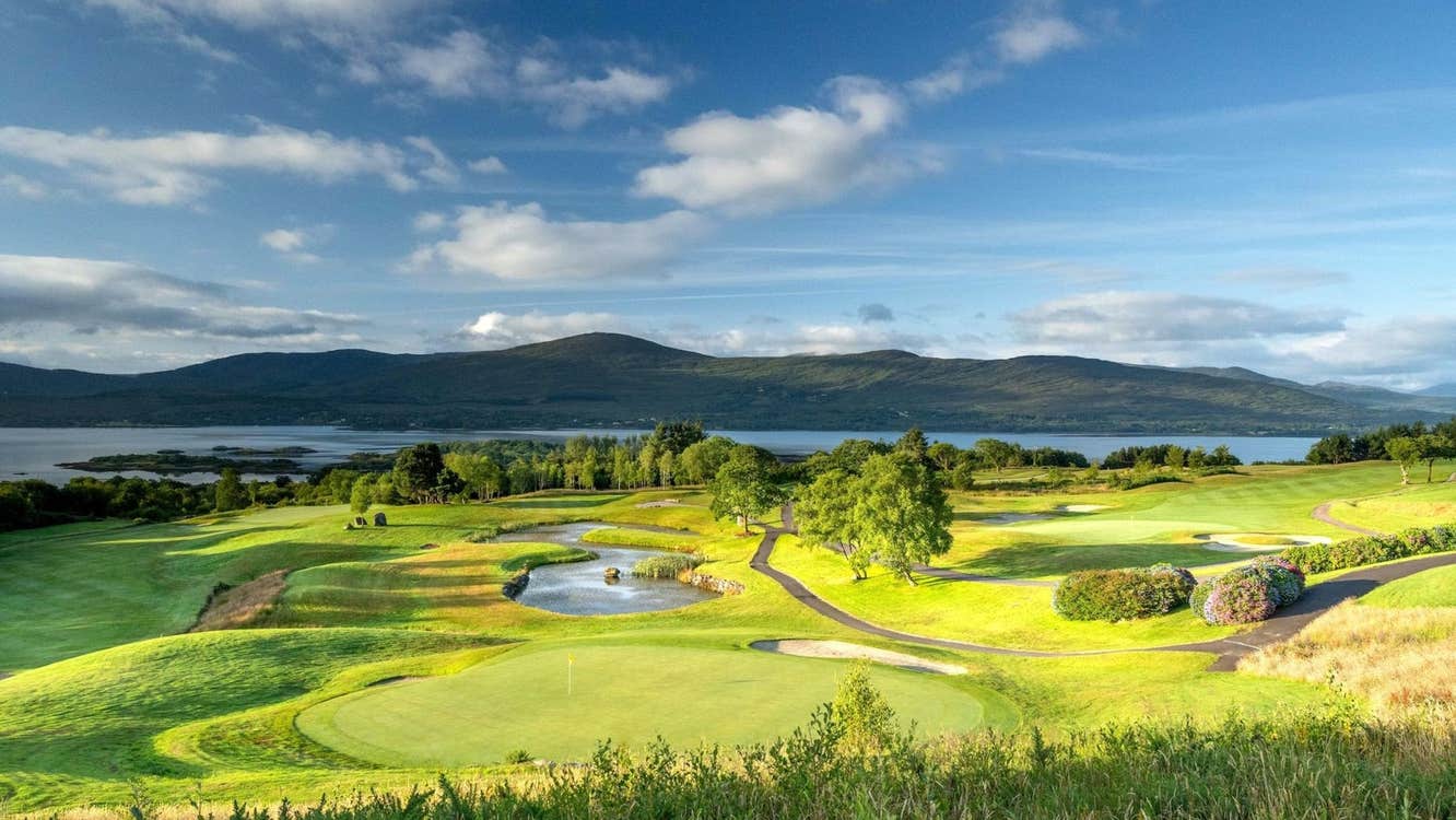 A golf course with a coastal view and mountains in the distance