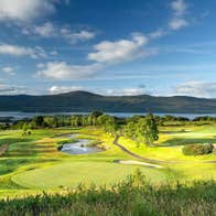 A golf course with a coastal view and mountains in the distance