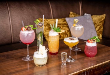 Selection of cocktails on a wooden bar table with cushions in the background