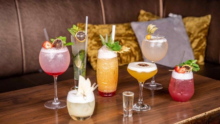 Selection of cocktails on a wooden bar table with cushions in the background