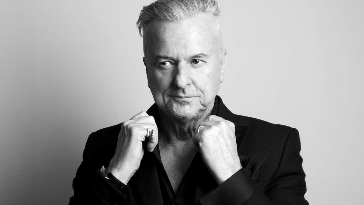 Black and white photo of man holding up the collar of his jacket.