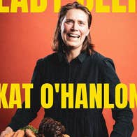 A smiling woman holding out a tray of raw vegetables