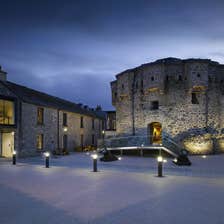 Castle at night time with pillar lights along the footpath in front